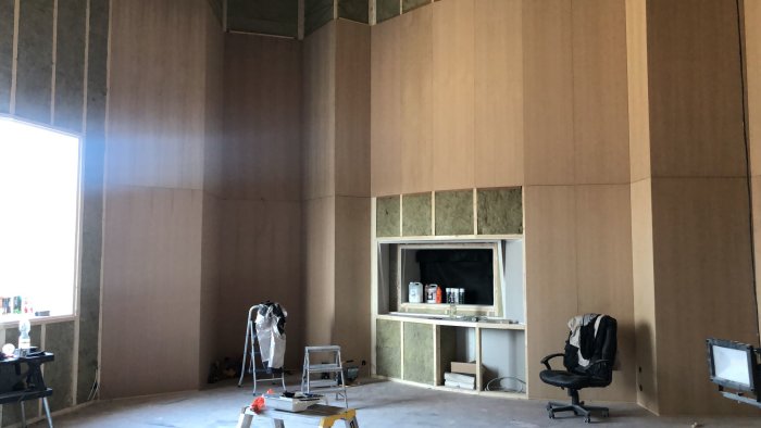 Musikstudio under konstruktion med obehandlade björkplywoodskivor på väggar och tak runt ett inbyggt fönster.
