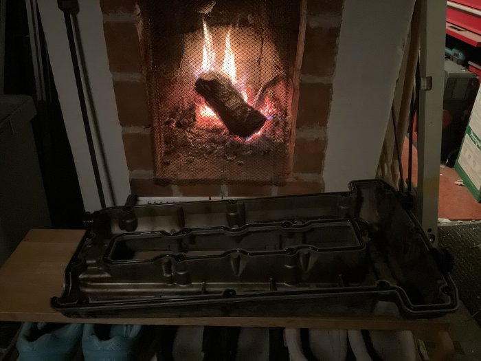 En oljetråg på ett bord framför en öppen spis med brinnande ved.