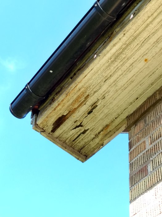 Slitna vindskivor med färgflagning på ett hus från 50-talet, behov av underhåll eller utbyte framgår.