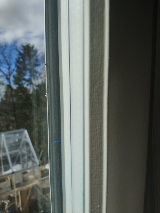Närbild på ett nytt fönster med synligt blått kabelavskal mellan glaset och den svarta tätningen.