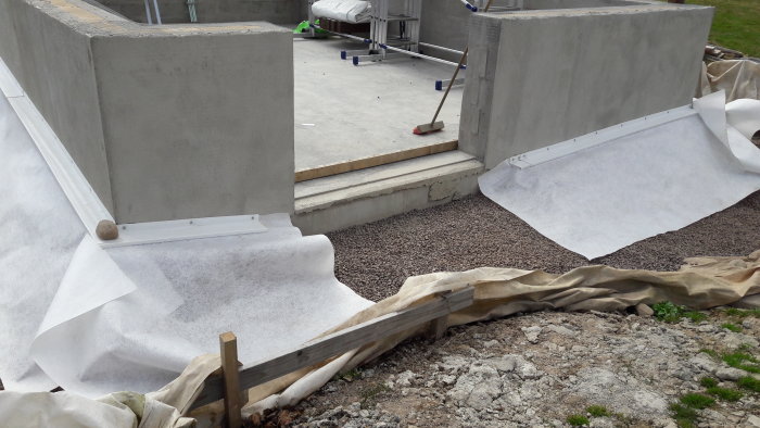 Renoveringsarbete på en plats för dränering med betongväggar och markskyddstextil.