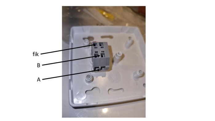Eluttag monterat på väggplatta med märkta anslutningar A och B samt en otydlig text "fik".
