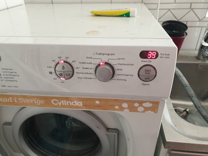 Tvättmaskinens kontrollpanel visas med inställningsknappar och en display som visar 0:03.