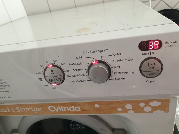 Kontrollpanelen på en Cylinda tvättmaskin med ett valt program och en röd lysande display som visar 1:28 timmar kvar.