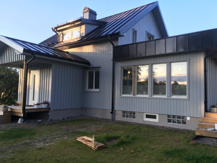 Ett hus med vindskiveplåtar monterade med farmarskruv, synliga från sidan på en grå fasad.