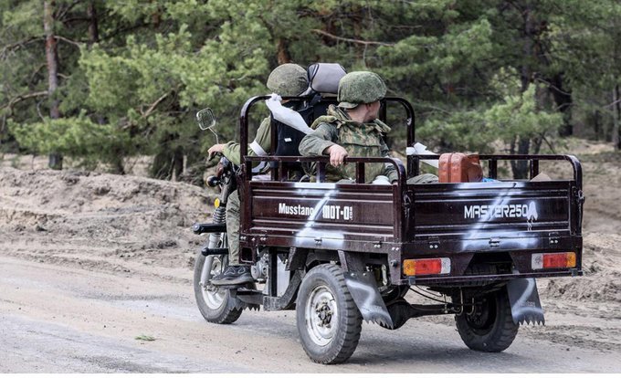 Två soldater i en militär taktisk Tuk Tuk på grusväg.