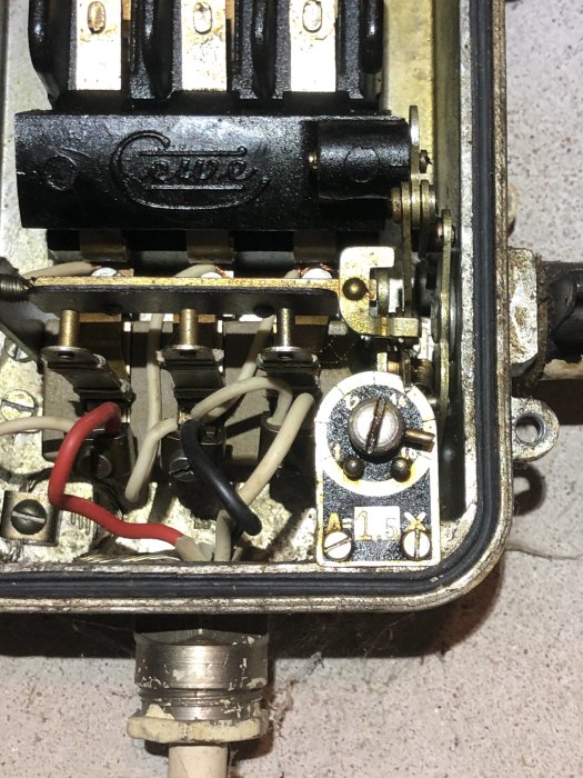 Elektrisk säkerhetsbrytare med ledningar och säkringar, delvis öppnad, monterad på en vägg.