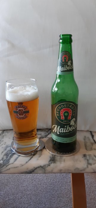 Flaska och glas av Pfungstädter Maibock öl på ett marmorbord.