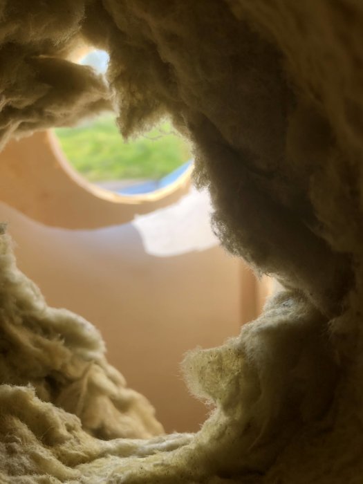 Isolerade väggen med synligt plastventilationsrör och ett hål genom väggen.