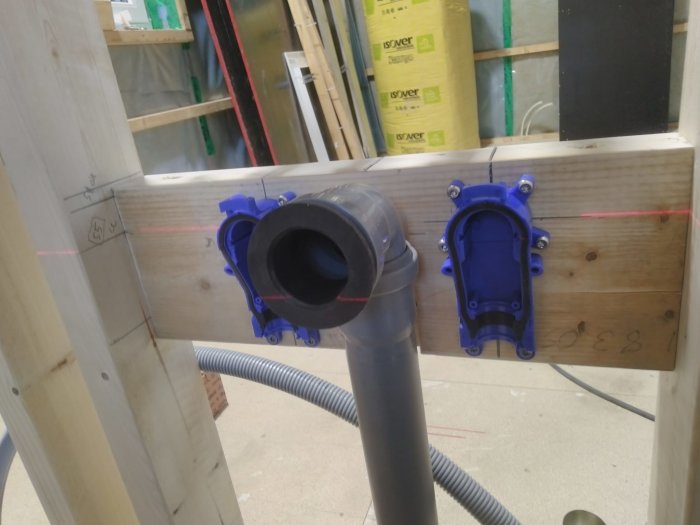 VV- och KV-installation med 50mm avloppsrör och 90-graders böj för handfatsavlopp monterade på trävägg.