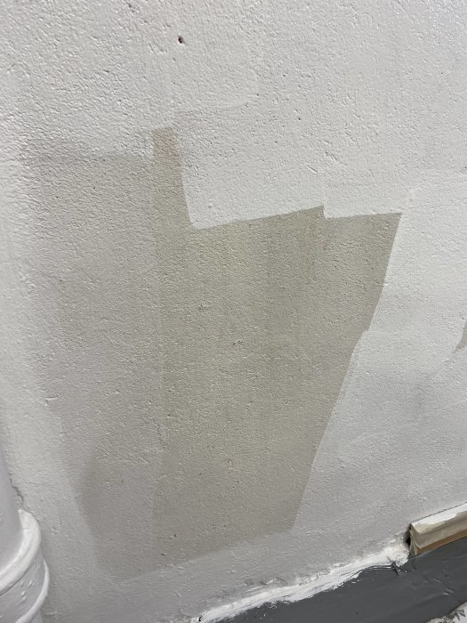 Nymålad vit yta på vägg som visar tydlig tonskillnad jämfört med den äldre vita färgen.