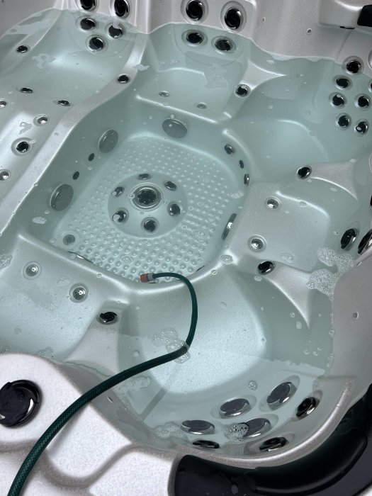 Tomt bubbelbadkar med droppar av vatten och synliga jetmunstycken.