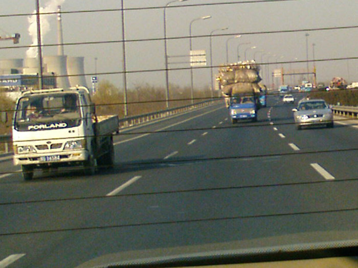 Utsikt från en bil visar en lastbil med återvunnet material på en motorväg i Peking, suddig av låg upplösning.