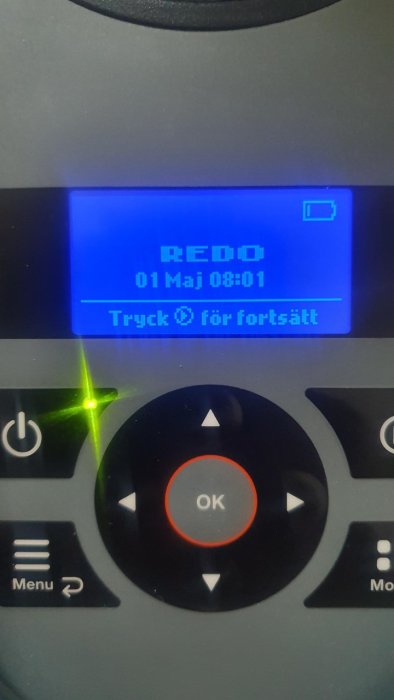 Display på en gräsklippare visar "REDO 01 Maj 08:01" och instruerar att trycka OK för att fortsätta.