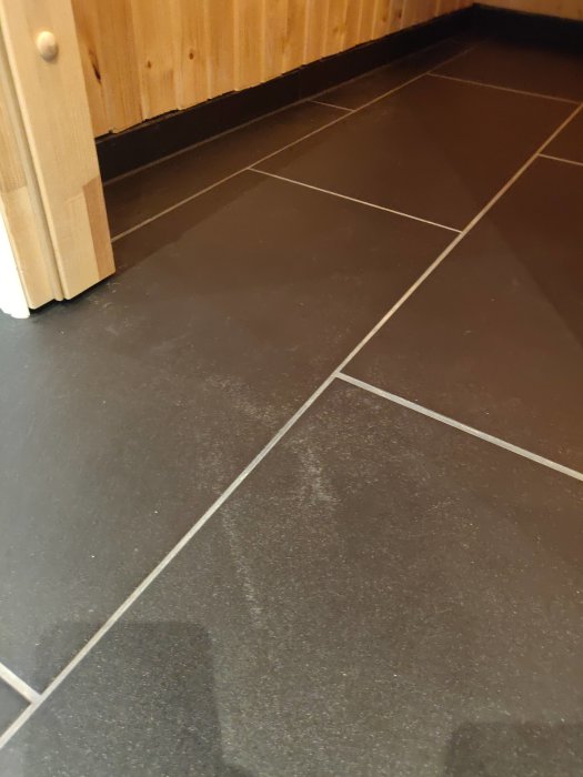 Svart klinkers i badrum med vita fläckar och prickar efter stående vatten.
