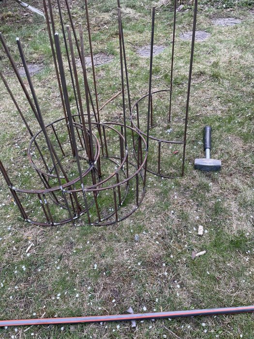 Metalliska planteringsstöd och verktyg på gräsmatta efter svets- och sliparbete.