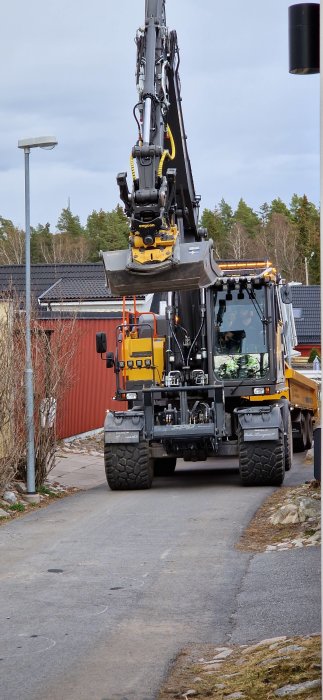 Grävmaskin som använts för att ta bort gräs och sten för att anlägga ny parkeringsplats nära huset.