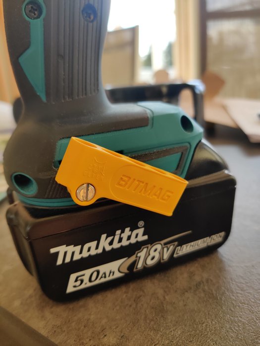 Makita 18V litiumjonbatteri och bitshållare på en arbetsbänk.