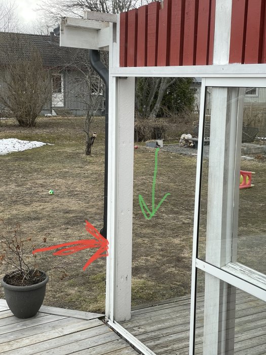 Altanplint som höjts markerad med röd pil på bild av husets hörn med altan och insynsskydd.