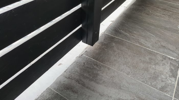 Balkonggolv med klinkers och tätningslösning vid stolpfäste.