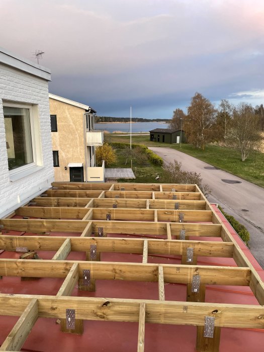 Uppbyggnad av trätrall nära hus med utsikt över havet vid skymningen.