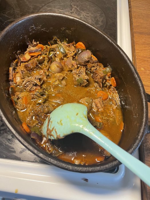 Hemlagad Boeuf Bourguignon med stekfläsk, rödlök, morötter och svampar i en gjutjärnsgryta.