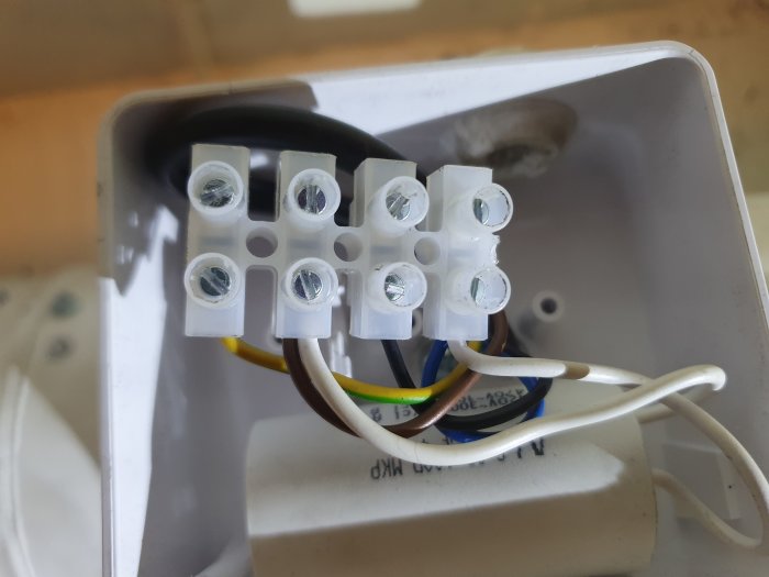 Elektrisk anslutning i en Östberg CK 125 A1 kanalfläkt med kablar anslutna till skruvplintar, i behov av korrekt inkoppling.