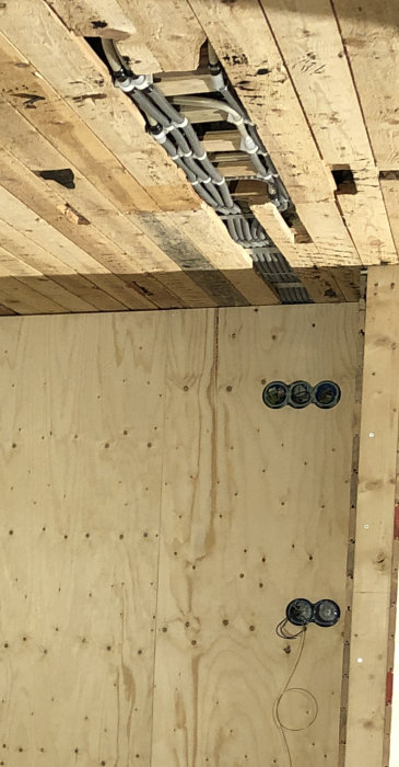 Kopplingsdosa med kabelskarv och enhetsinstallation på trävägg, oavslutad eldragning i renoveringsprojekt.