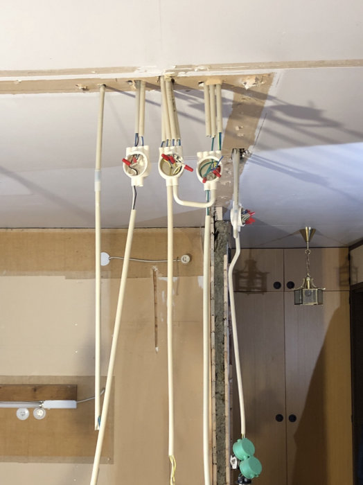 Elektriska installationsrör och kopplingsdosor mot en vägg under renovering med synliga elskarvar.