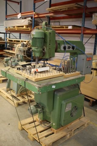 Industriell grön maskin på en pall i ett lagerlokalsutrymme.