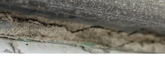 Närbild på lossnat spackel från poolkanten som visar skadan och behovet av omfogning.