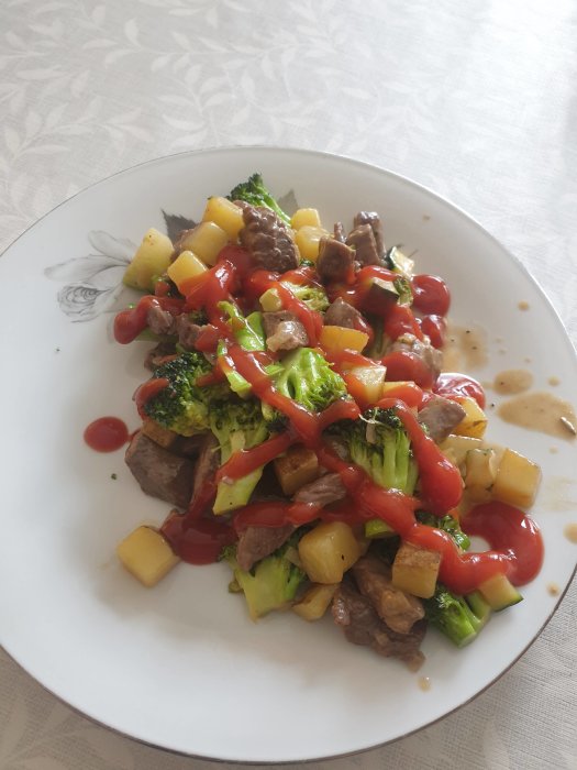 Tallrik med hemgjord pyttipanna bestående av kött, potatis, broccoli och ketchup.