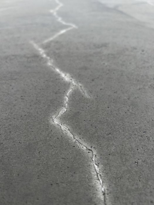 Närbild av en spricka i en nyligen gjuten betongplatta.