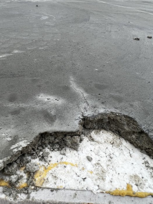 Nyutgjuten betongplatta med tydlig sprickbildning och skadad kant.
