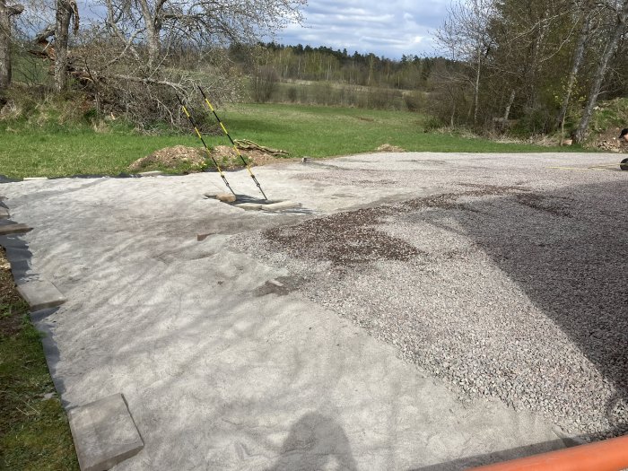 Pågående arbete med markförberedelser visar grus, duk och skottkärra på en yta ett år in i projektet.