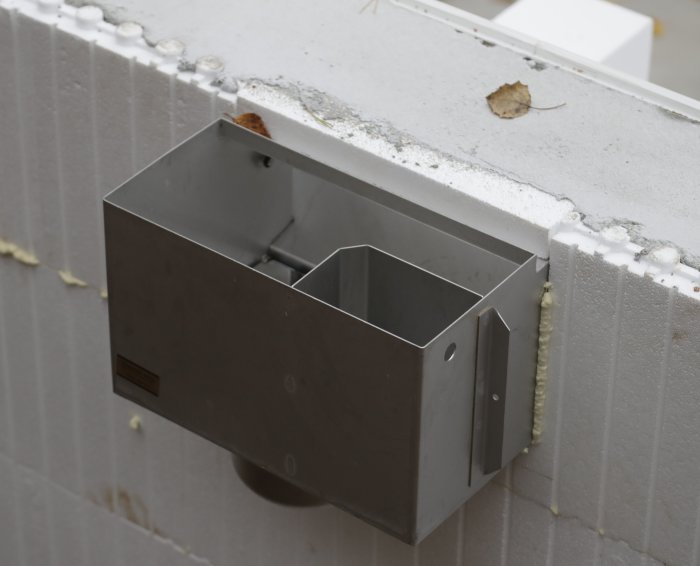 Bräddavlopp monterat på cellplastblock vid kanten av en poolkonstruktion, med en stensarg ovanpå.