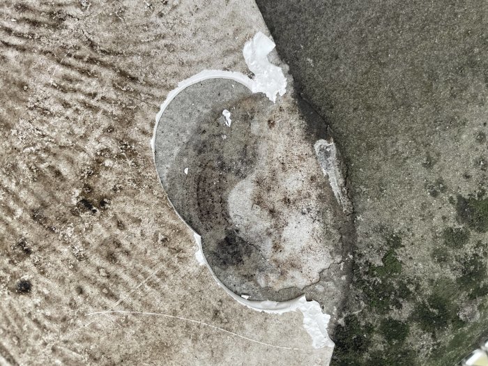 Vit färg spilld på en strukturerad cementplatta, några bitar färg brutna och borttagna.