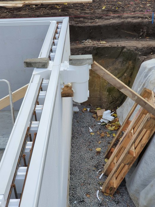 Bräddavlopp monterat under en snäpplist vid en pool under konstruktion, med synlig höjdjustering.