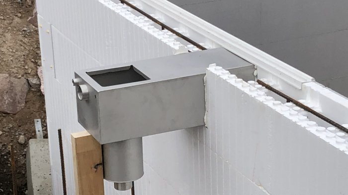 Detaljbild av en poolkant med monterad rostfri infälld poolrenare vid sidan av vita isoleringsblock.