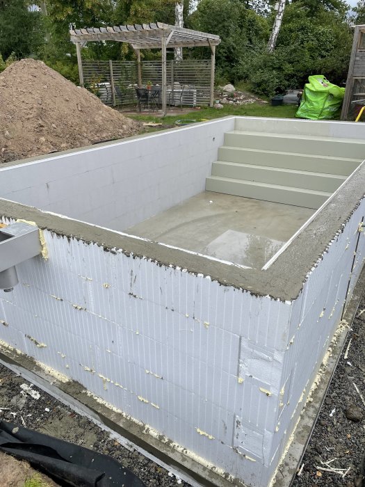 Grund av ett hus under konstruktion med isolerblock och nylagt betonggolv.