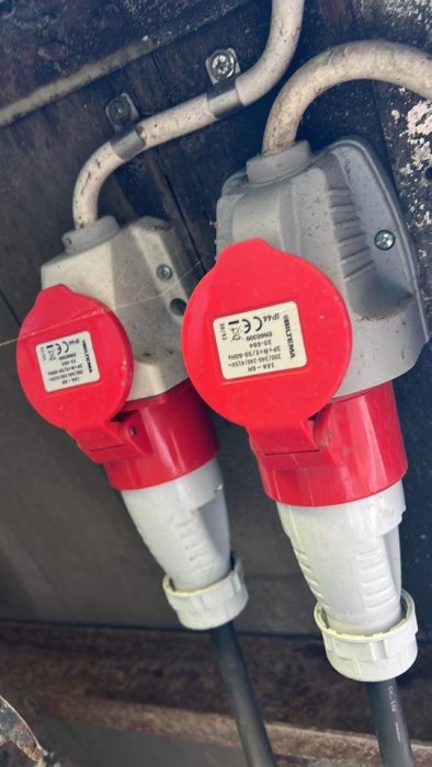 Två röda industriella eluttag monterade på en vägg, säkrade med 20 ampere.