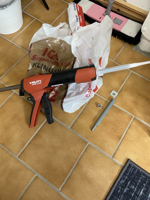 Kemankare, konsol och injektionspistol på ett klinkergolv med bakgrunden av shoppingkassar.