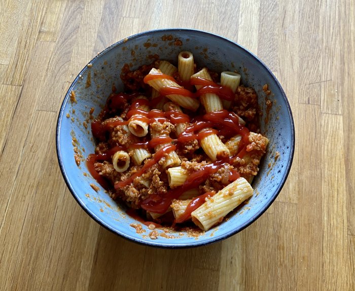 En skål med sojafärssås och pasta toppad med ketchup, tillagad enligt beskrivet recept.