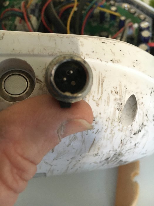 Hand håller en hoverboards skadade laddningskontakt med en avbruten pin och synliga anslutningar.