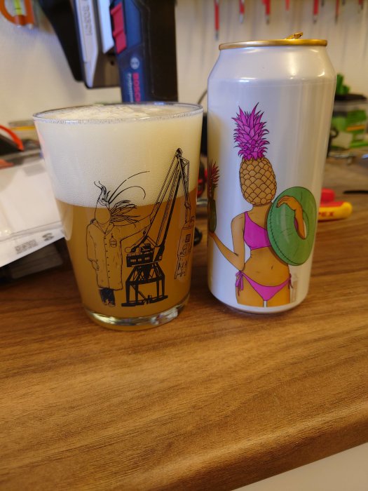 Ett glas öl med tjockt skum bredvid en burk dekorerad med tropiskt motiv.