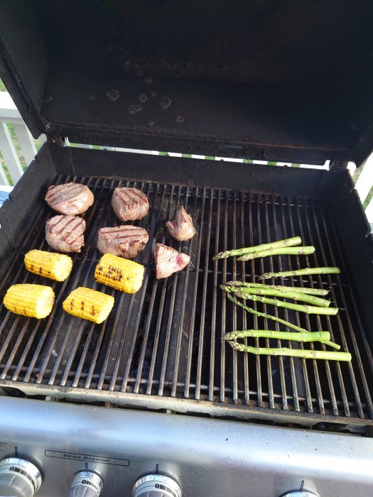 Grill med grillade rostbiffar, majs och sparris.