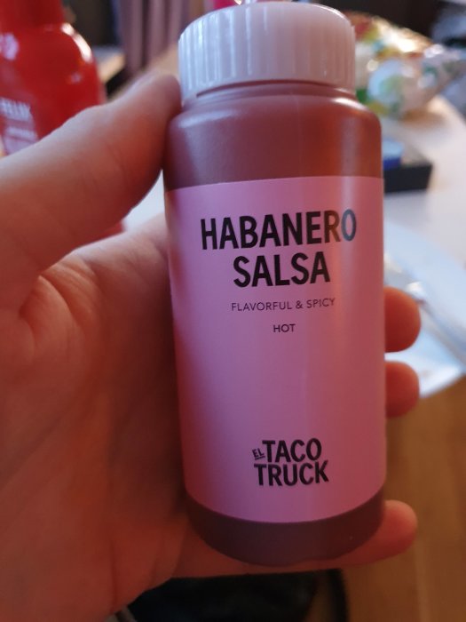 Hand håller en flaska Habanero Salsa från El Taco Truck, beskrivning anger att den är smakrik och stark.