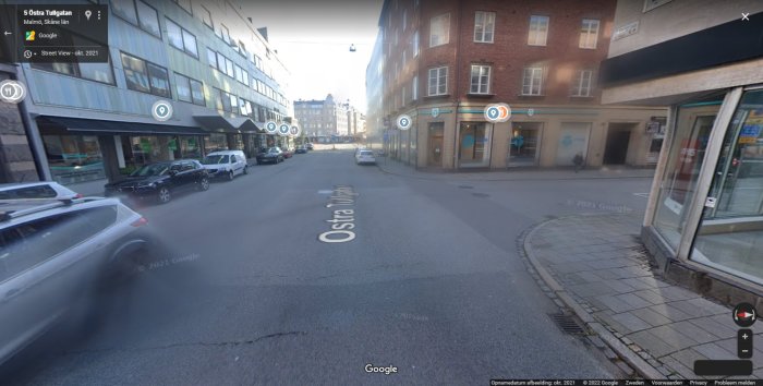 Gatuscen i stadsmiljö med flera oskyltade korsningar och parkerade bilar vid vägkanten.