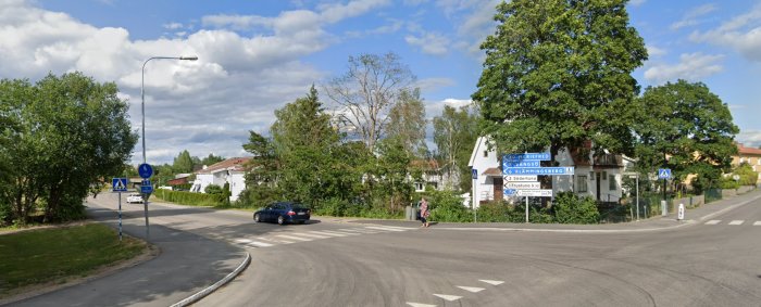 Korsning utan varningstriangel för väjningsplikt, ett gatunamnsskylt och bil på Mariefredsvägen.