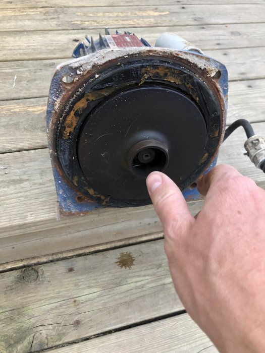 Person pekar på drivaxeln av en demonterad VALCO 139 j-pump på ett trägolv.